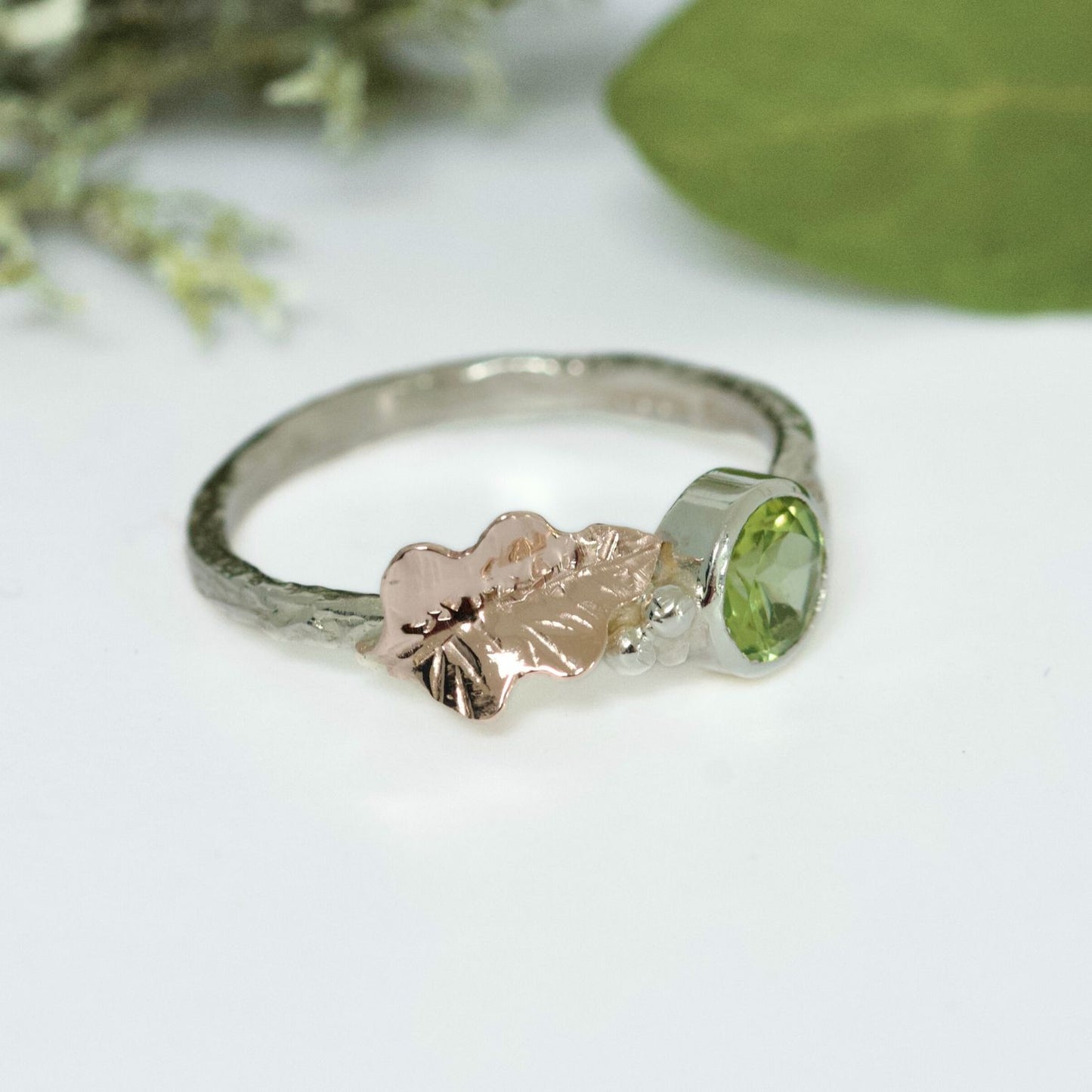 Peridot, August Birthstone, set on a 9ct white gold twig band with a contrasting hand pierced and engraved 9ct rose gold oak leaf. Alternative Nature Inspired Engagement Ring.
