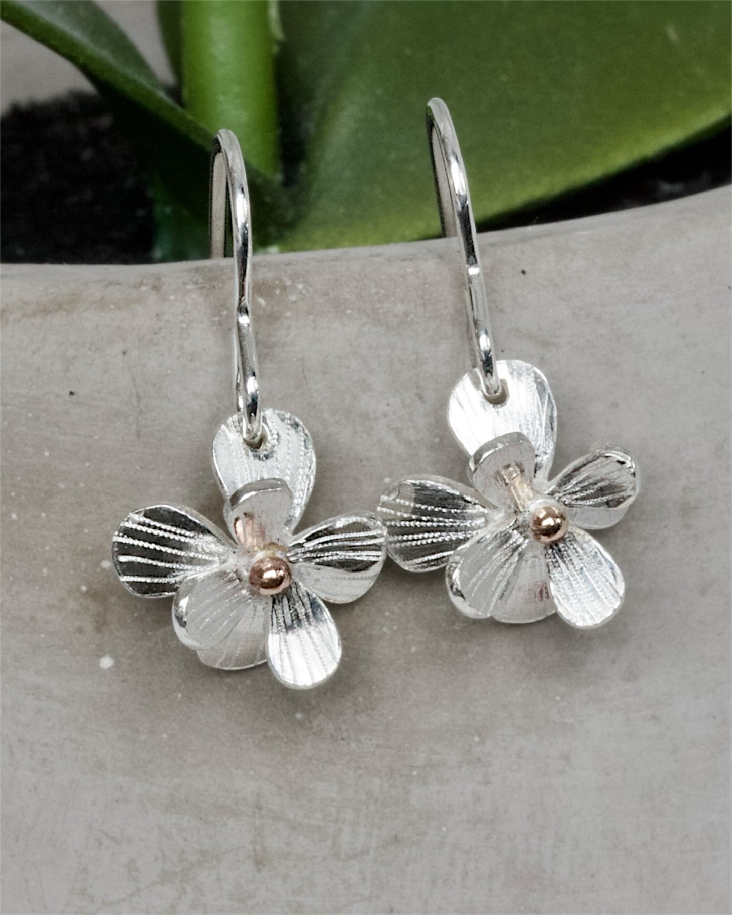 Sculptural small sterling silver flower earrings. Drop Dangle style in sterling silver with a solid rose gold centre. Mixed Metal Flower Earrings.