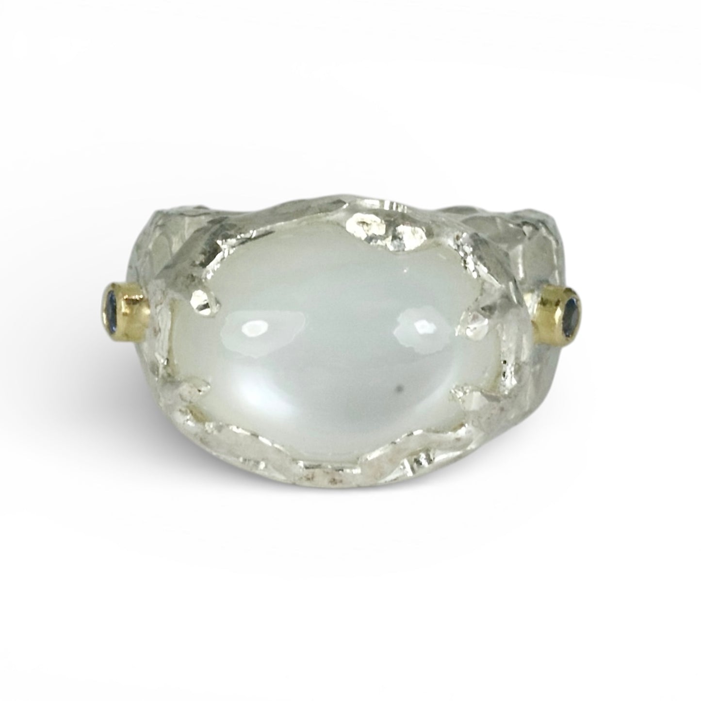 Sculptural sterling silver ring set with a large oval cabochon moonstone. Blue sapphires and 18 carat gold accents on the sides of the ring.