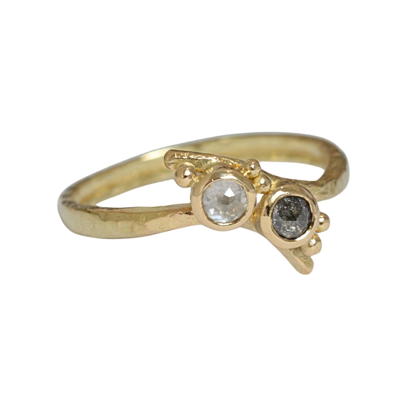 Black rose cut diamond set next to a white rose cut diamond on a hand forged 18 carat crossover band and gold granulation.