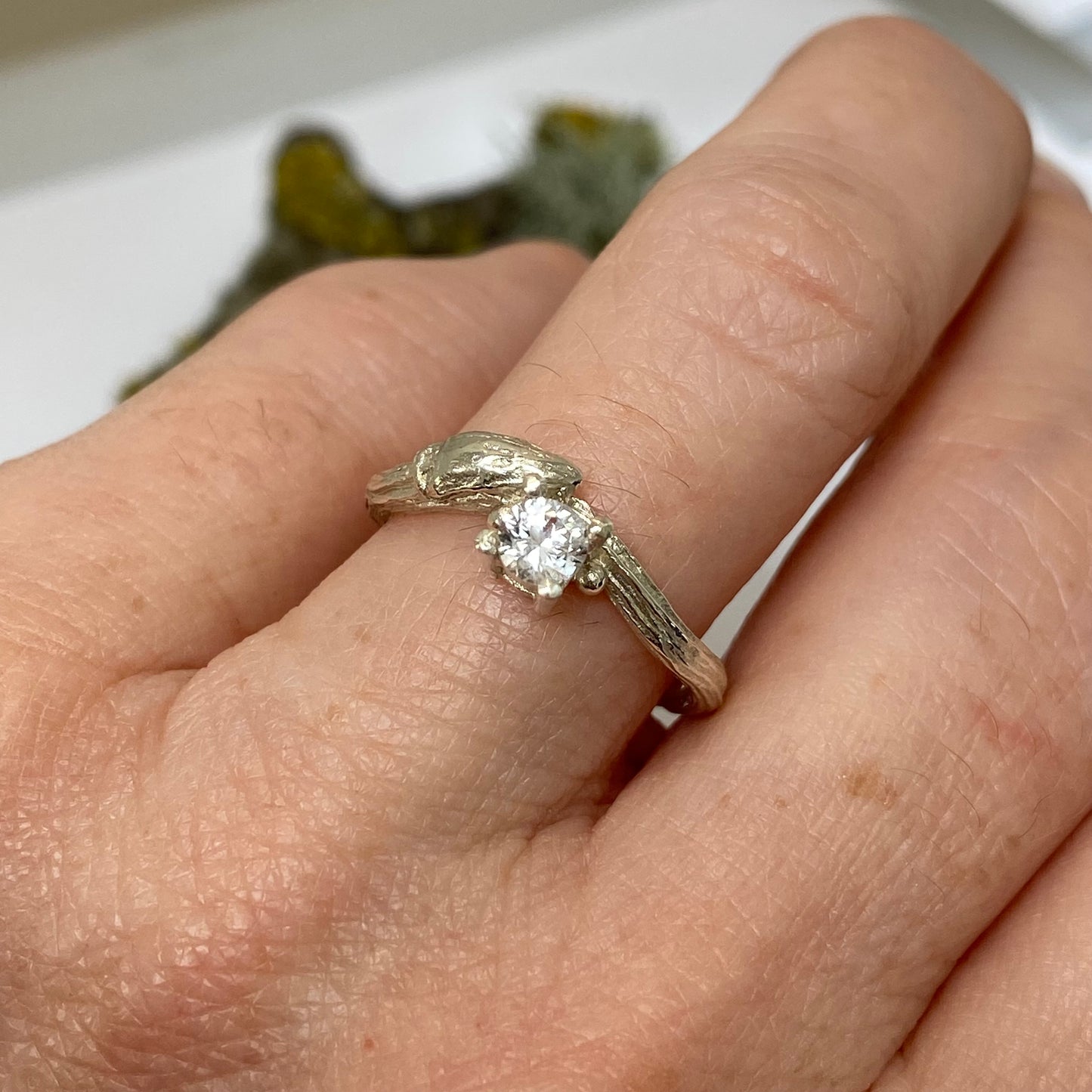 Cast from a real willow twig in 9ct gold, showing the willow bud and bark details, this nature inspired twig ring is set with a brilliant cut natural white sapphire.