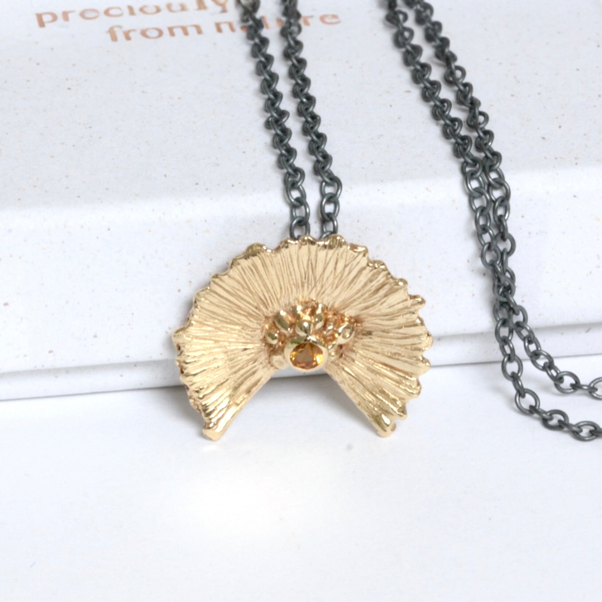 orange sapphire and gold sunset necklace on a black silver chain.