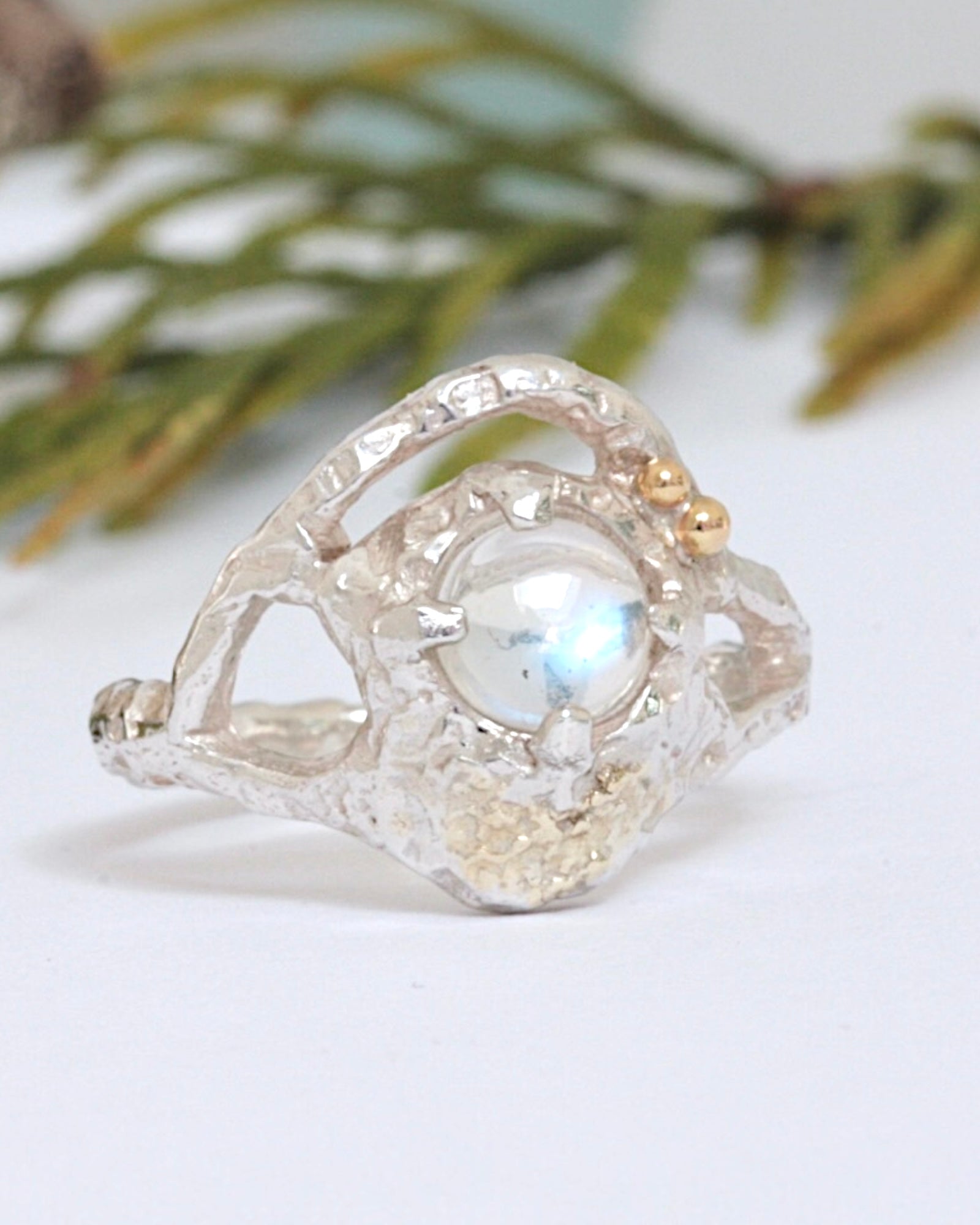 Elegant sterling silver ring showcasing a glowing 5mm blue moonstone, with two gold accent balls and fused 18ct gold details along a textured, flowing band.