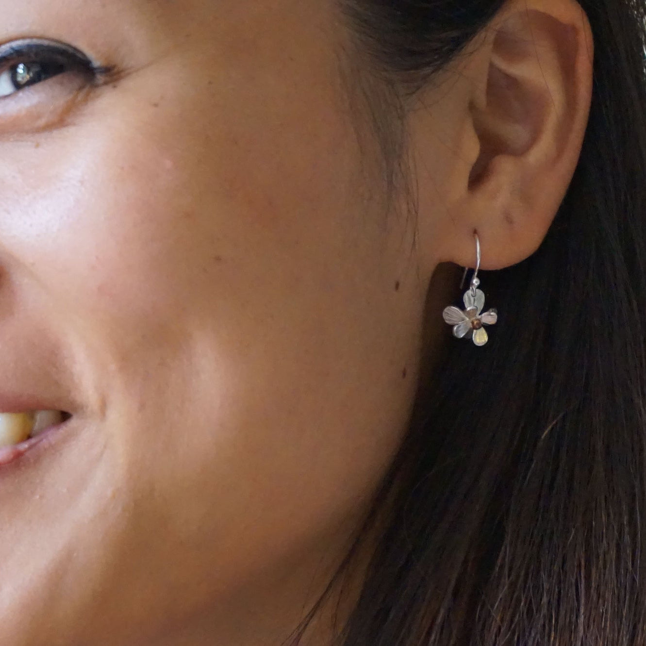 Close-up of a woman wearing a floral earring.