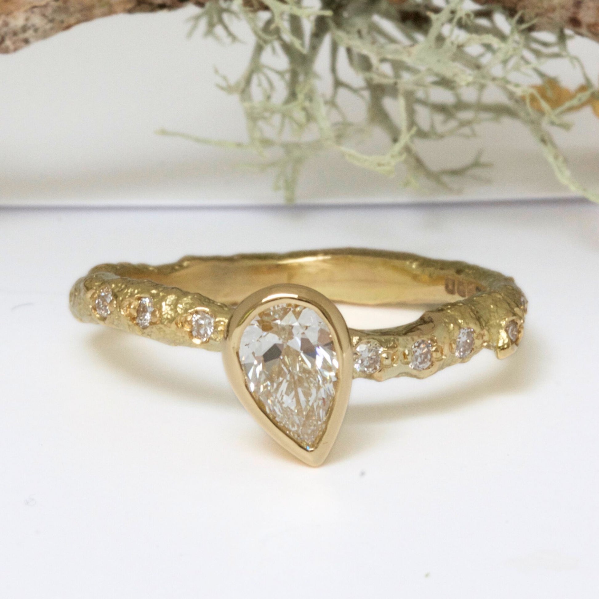 solid gold nature ring cast from a real twig and set with a lab grown pear shaped diamond and pave set diamonds in the band.