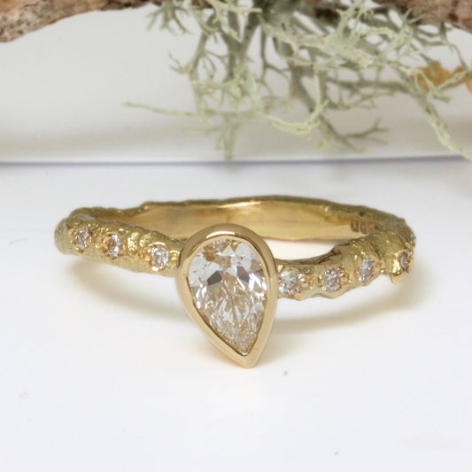 solid gold nature ring cast from a real twig and set with a lab grown pear shaped diamond and pave set diamonds in the band.