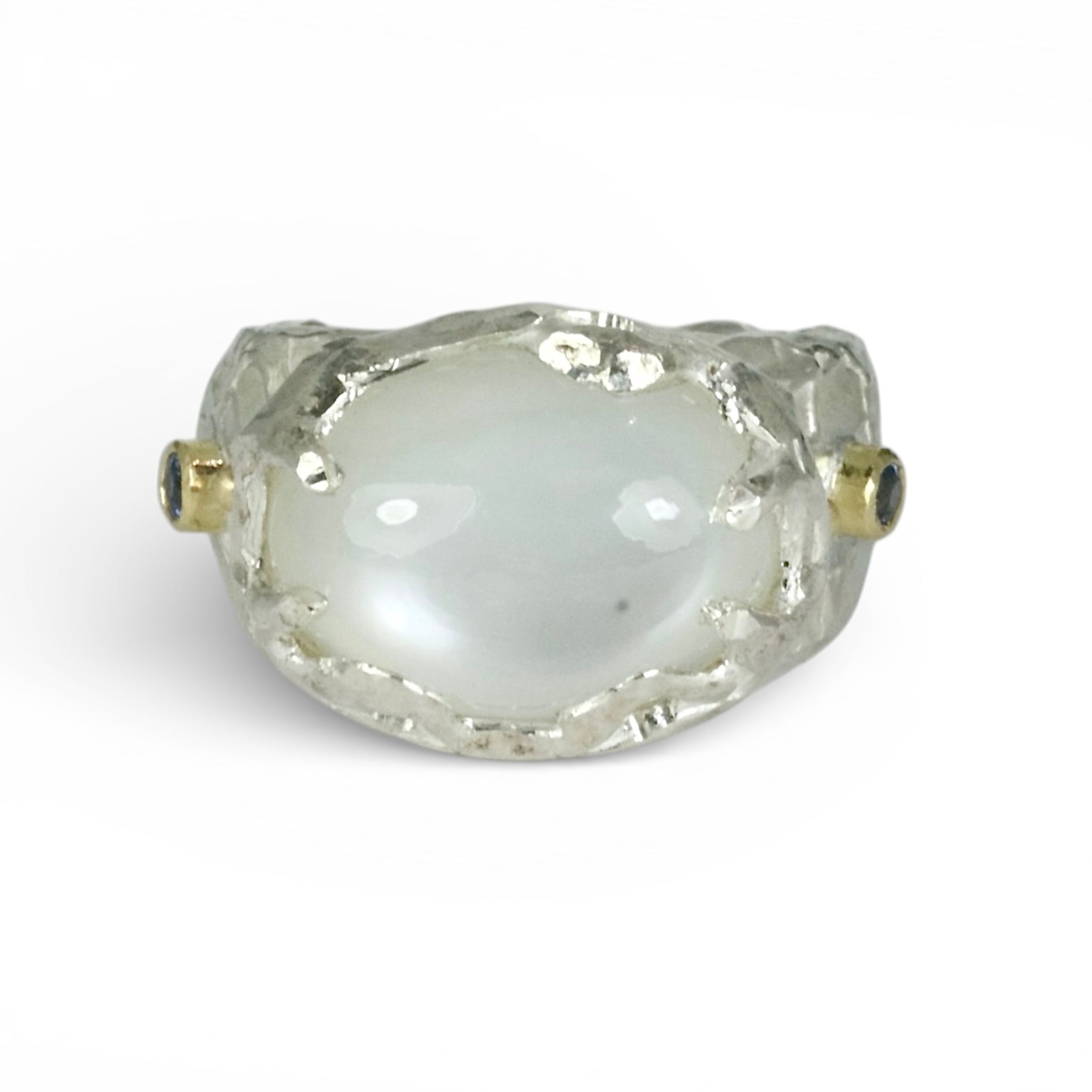 Sculptural sterling silver ring set with a large oval cabochon moonstone. Blue sapphires and 18 carat gold accents on the sides of the ring.