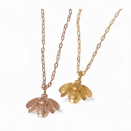 Two gold bee necklaces on white background