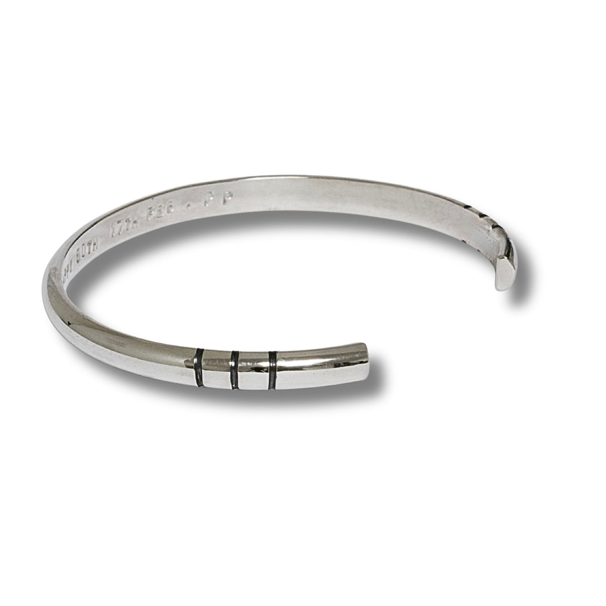 A polished solid sterling silver cuff bracelet with three black carved stripes on the front, displayed on a clean white background.