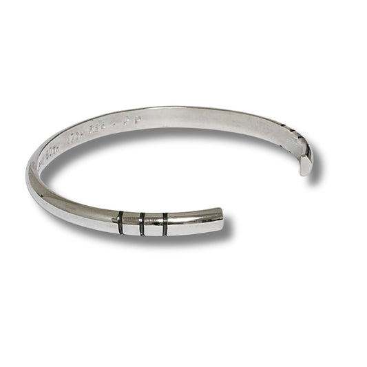 A polished solid sterling silver cuff bracelet with three black carved stripes on the front, displayed on a clean white background.