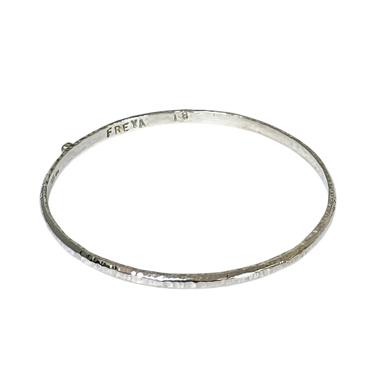 A hammered silver bangle bracelet with the brand name 'FREYA' and '18' stamped inside, shown on a plain white background.