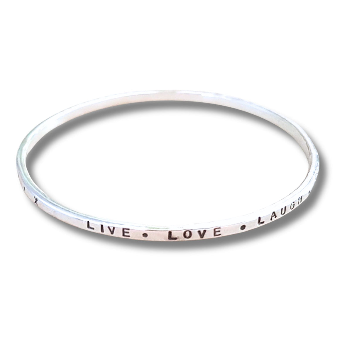 A slim  silver bangle bracelet with the words 'LIVE • LOVE • LAUGH' hand stamped on the band, shown against a plain white background.