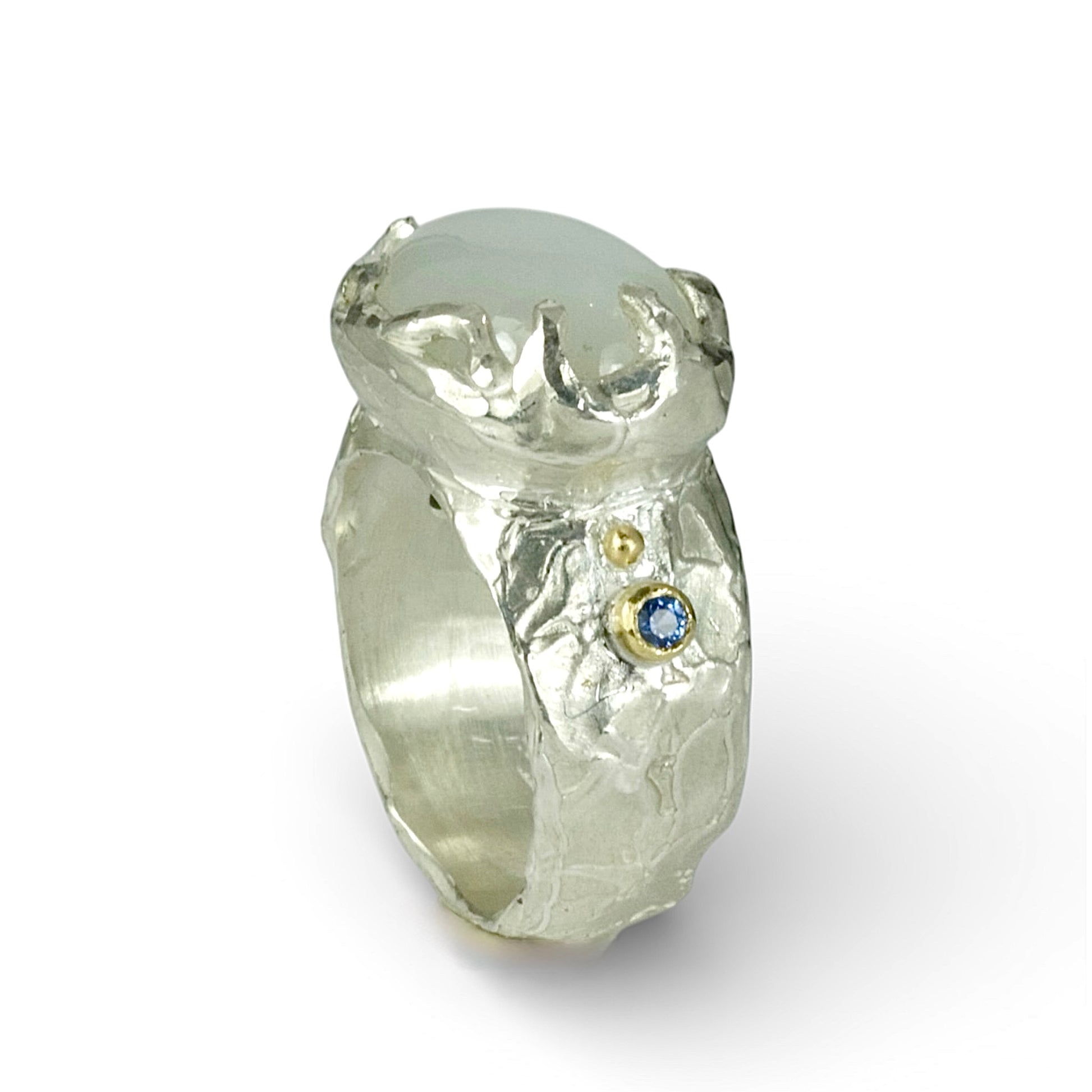 Sculptural sterling silver ring set with a large oval cabochon moonstone. Blue sapphires and 18ct gold accents on the sides of the ring.
