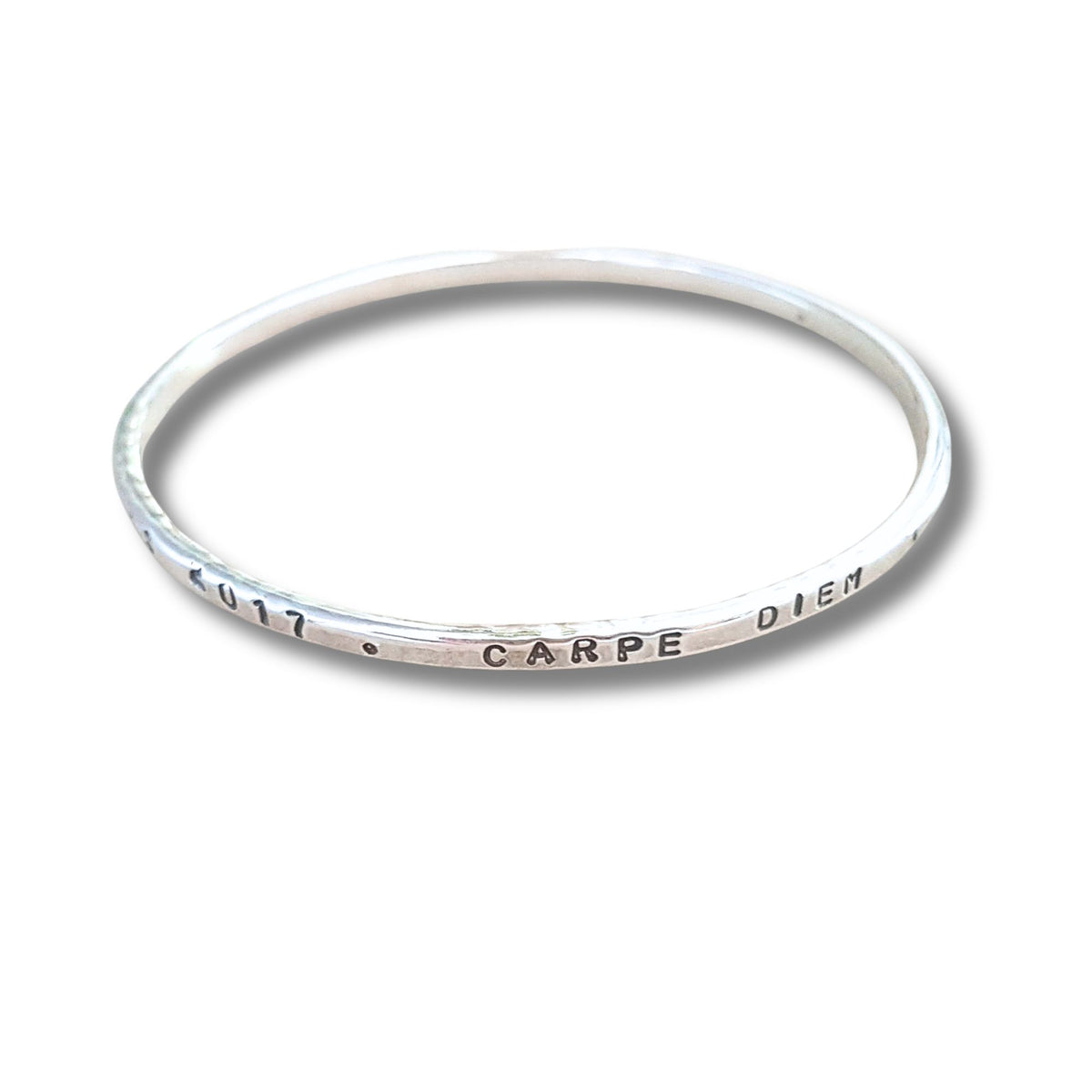 A slim silver bangle bracelet with a hammered texture, featuring the stamped text '2017 . CARPE DIEN' on a plain white background.