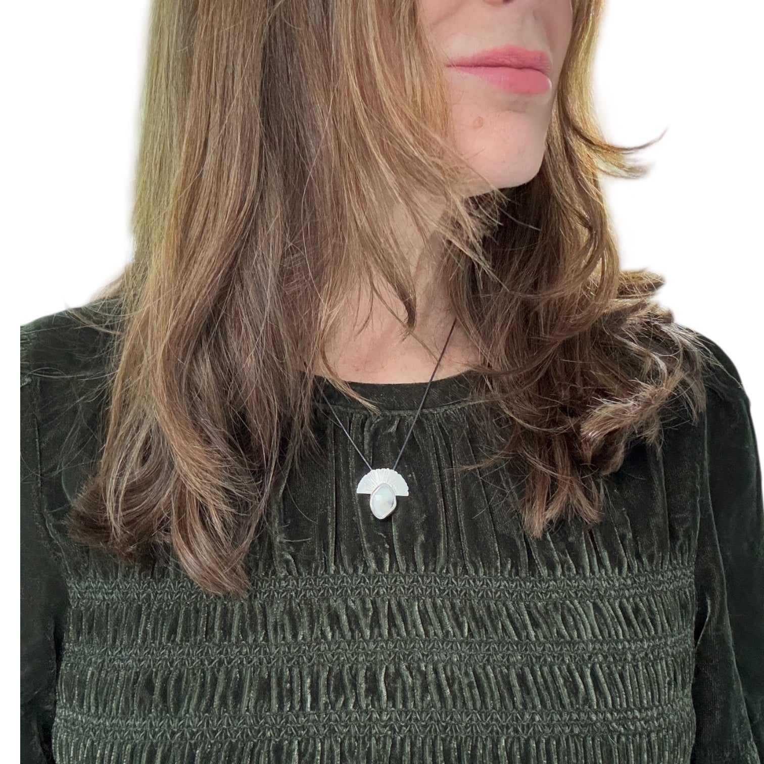 This handcrafted black and white silver pendant features a rustic rose-cut sapphire cradled in organic, sculpted metal. Its monochrome palette of cool silver and misted stone evokes mountain horizons and soft morning light, while the textured silver fan rises like a quiet sun over the landscape.