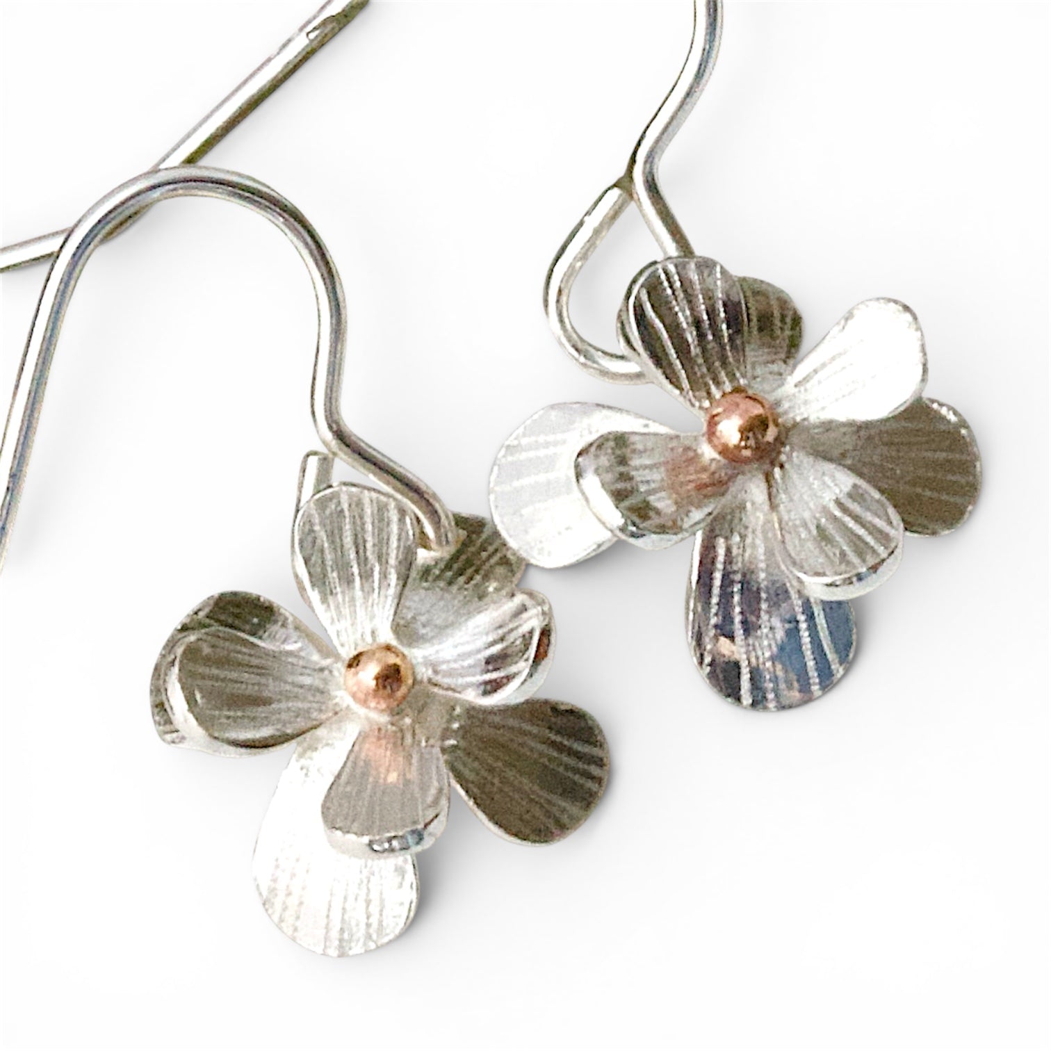 Sculptural small sterling silver flower earrings. Drop Dangle style in sterling silver with a solid rose gold centre. Mixed Metal Flower Earrings.