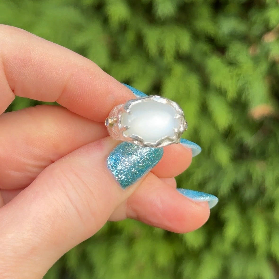 Sculptural sterling silver ring set with a large oval cabochon moonstone. Blue sapphires and 18ct gold accents on the sides of the ring.