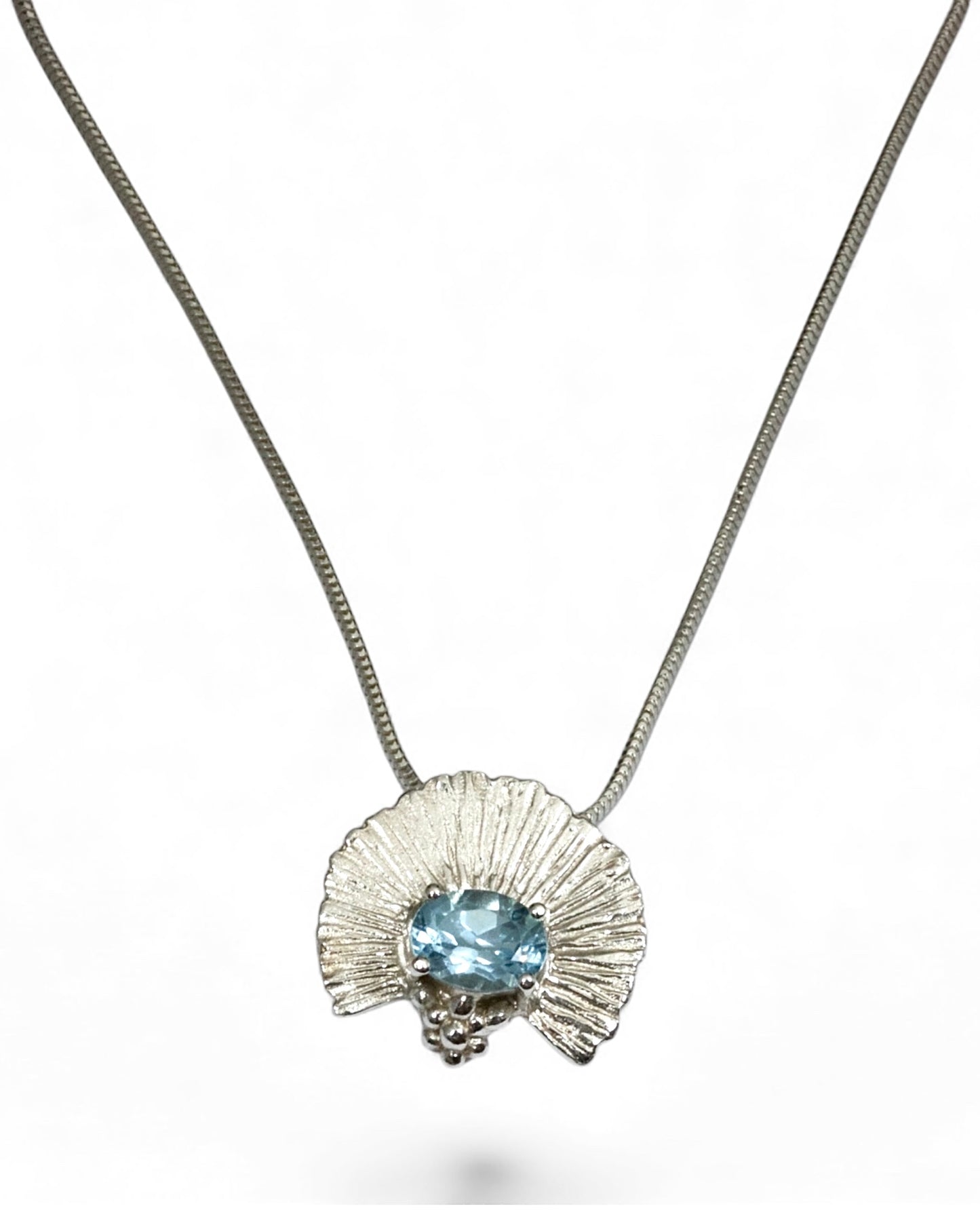 Silver necklace with a pendant featuring a blue gemstone on a white background