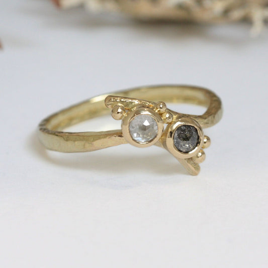 The crossover band, individually forged from recycled 18ct gold, carries a hammered texture that reflects its artisanal origin. Tiny granules of gold and two natural rose-cut diamonds accent the band, adding sparkle and a sense of timeless artistry.