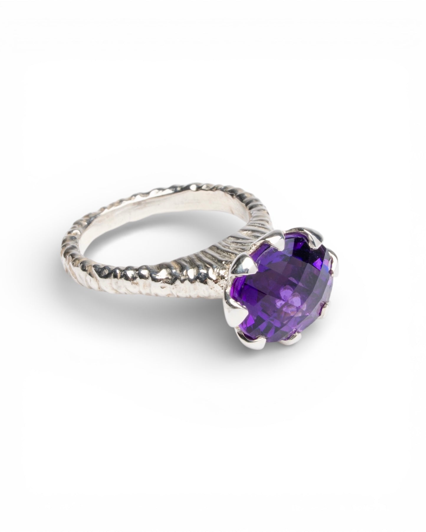 Hand-carved sterling silver ring with a high tulip petal-style bezel holding a dark purple oval chequerboard-cut amethyst, sculptural carved shank and elegant raised setting.