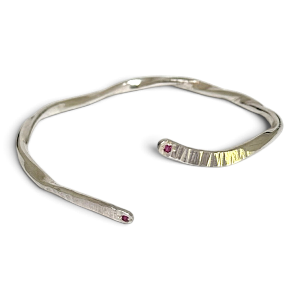 A silver open cuff bracelet with a textured, organic wavy design and two small red gemstone accents, shown on a plain white background. Ruby wedding anniversary gift, July birthday gift.