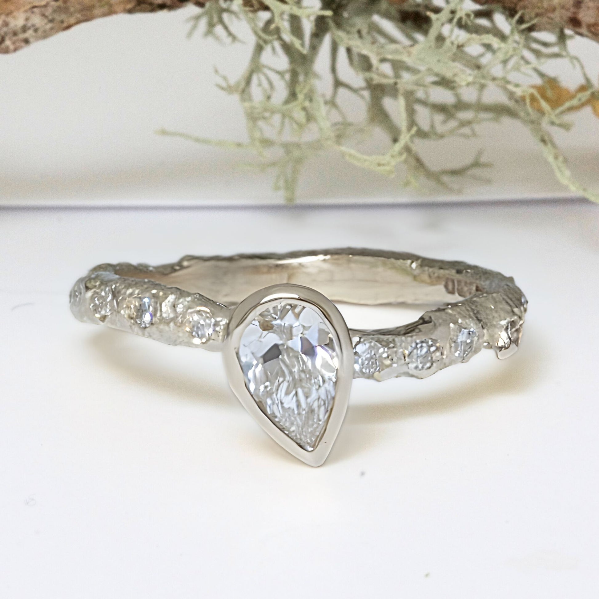 Organic twig engagement ring set with pave diamonds and a pear shaped lab grown half carat diamond.