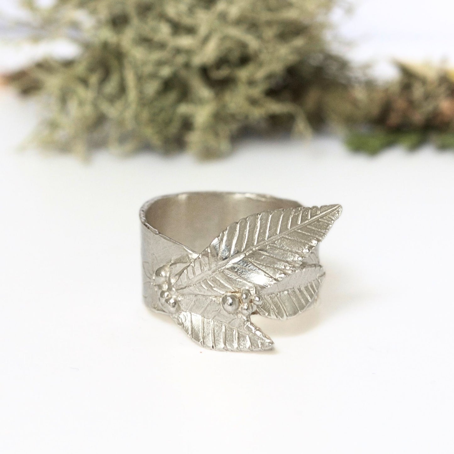 Arts and Crafts style handmade silver nature ring featuring engraved floral design and carved sculptural leaves.