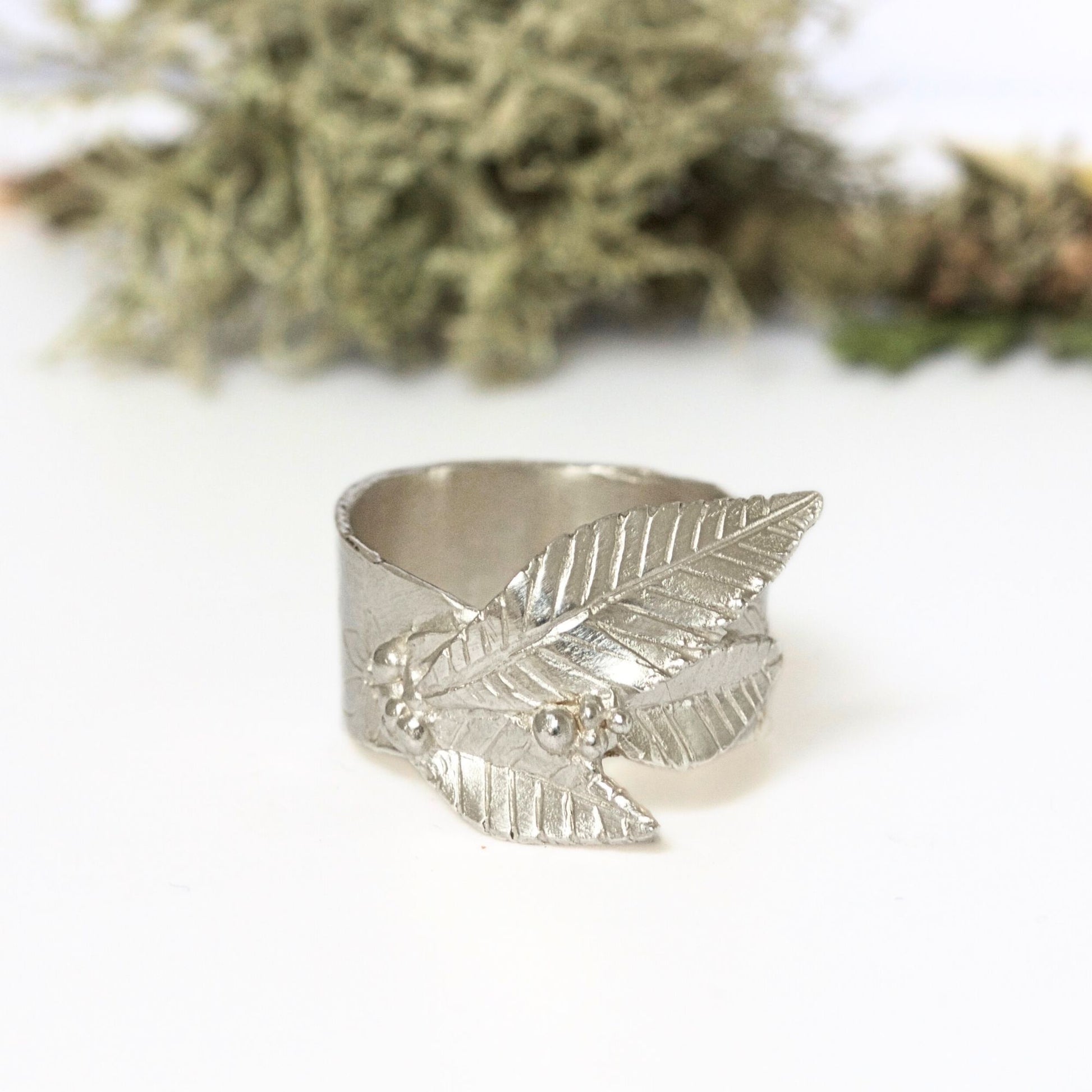 Arts and Crafts style handmade silver nature ring featuring engraved floral design and carved sculptural leaves.