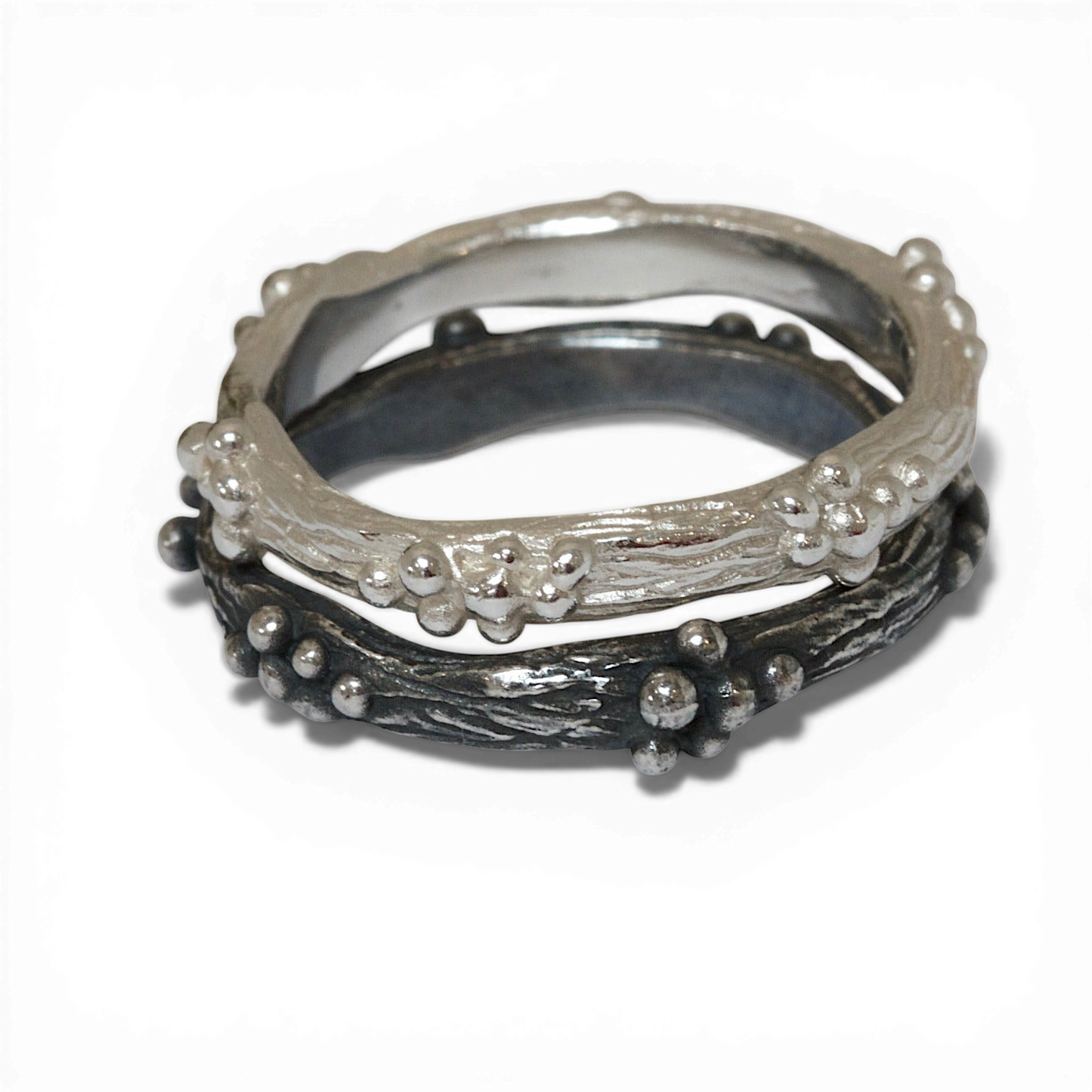 Stack of silver rings with textured band and bead details on a white background