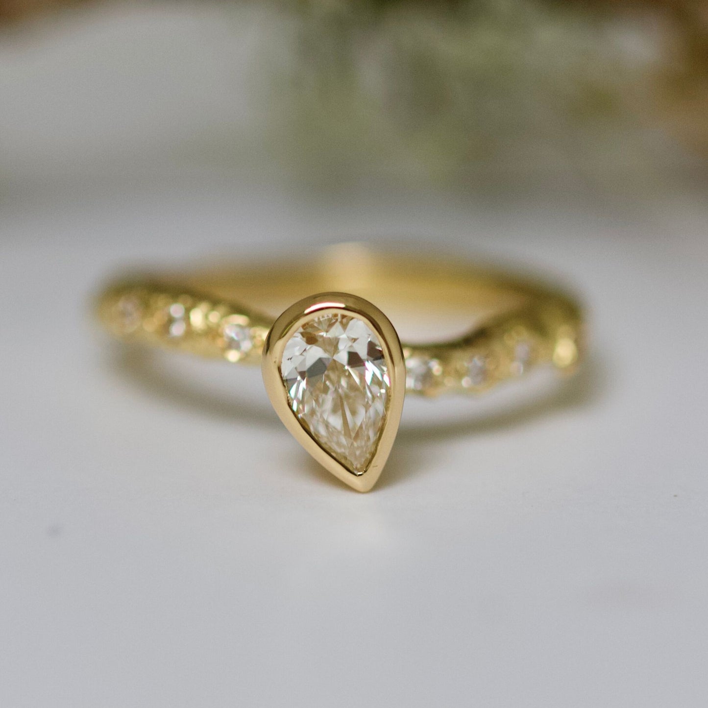 Nature yellow gold alternative engagement ring with a teardrop cultured diamond.