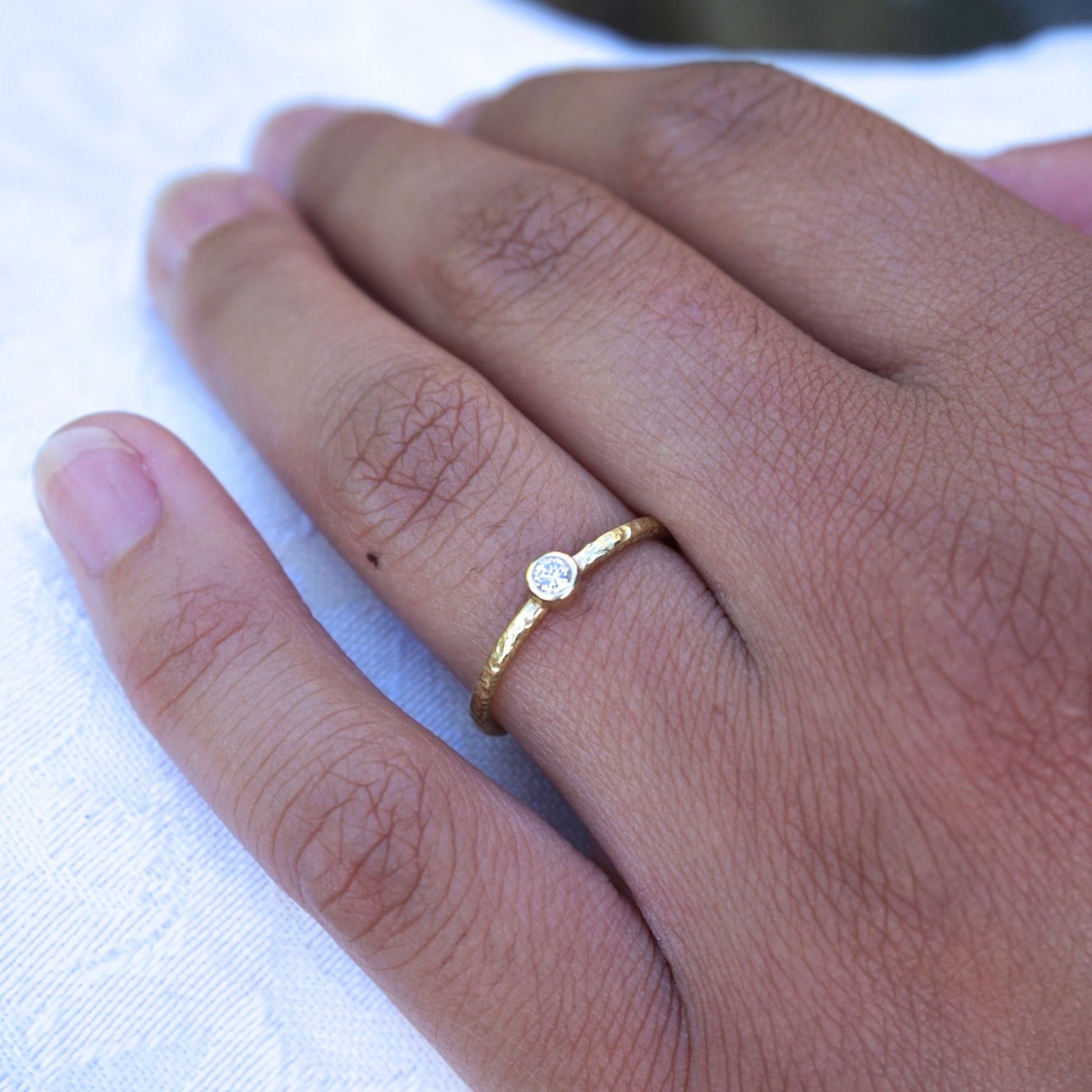 bezel set natural diamond on a textured 18ct gold band.